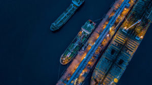 Aerial view Crude oil tanker under cargo operations on typical shore station with clearly visible mechanical loading arms and pipeline infrastructure
